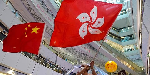 People wave a Hong Kong flag and a Chinese national flag as they watch Olympics events. (Photo | AP)