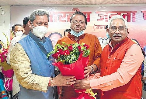 New Uttarakhand Chief Minister Pushkar Singh Dhami (C) with TS Rawat (L) and state BJP head Madan Kaushik in Dehradun. (Photo | PTI)