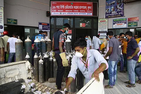 In this picture taken on July 2, 2021 Men unload medical oxygen cylinders at the entrance of a government hospital dedicated to treat Covid-19 coronavirus patients in Khulna. (Photo | AFP)