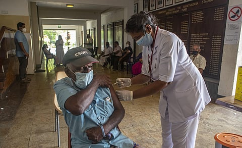 A Sri Lankan health worker administers a COVID-19 vaccine to an elderly man during a vaccination drive in Colombo. (Photo | AP)