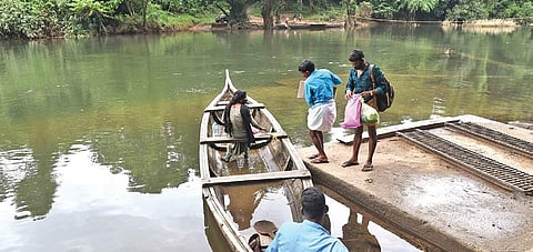 Tribal people of Kuchippara colony crossing the Kuttampuzha river in a country boat. (Photo | Albin Mathew/EPS)
