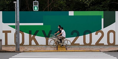 Citizens People cycle along the wall installed to close off a park being prepared for the Olympics and Paralympics Games in Tokyo. (Photo | AP)