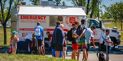 A Salvation Army EMS vehicle is setup as a cooling station as people lineup to get into a splash park while trying to beat the heat in Calgary, Alberta in Canada. (File Photo | AP)
