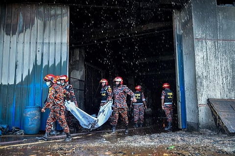 Firefighters recover the body of a deceased who died in the fire that broke out a day before in a beverage and food factory in Rupganj in the district Narayanganj on July 9, 2021. (Photo | AFP)