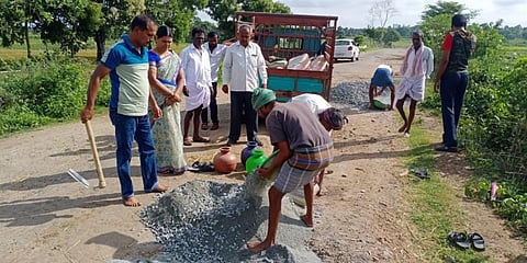 Assistant sub-inspector S Doreswamy helps fill the pockmarked road in in HD Kote taluk. (Photo | Express)