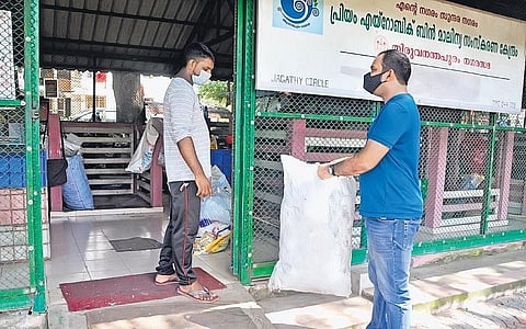A person handing over plastic waste collected from household to a worker at the aerobic bin facility at Jagathy in Thiruvananthapuram | B P Deepu