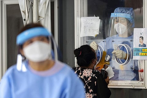 A medical worker wearing protective gear in a booth, takes sample from a visitor during a COVID-19 testing at a coronavirus testing site in Seoul, South Korea, Wednesday, Aug. 11, 2021. (Photo | AP)
