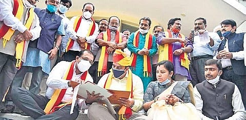 Kannada and Culture Minister Sunil Kumar signs on a file while seated on the steps of Ravindra Kalakshetra in Bengaluru on Wednesday | Express