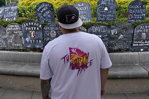 A man looks at cardboard gravestones with the names of victims of opioid abuse outside the courthouse where the Purdue Pharma bankruptcy is taking place. (Photo | AP)