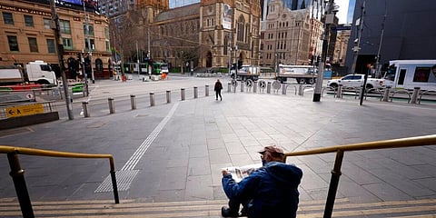 A man reads a newspaper on the steps of Flinders Street Station in Melbourne, Australia, Wednesday, Aug. 11, 2021. (photo | AP)