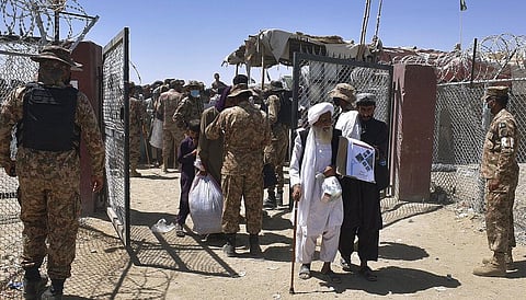 Pakistani soldiers stand guard while stranded people walk towards the Afghan side at a border crossing point, in Chaman, Pakistan.