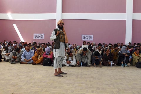 A Taliban fighter stands guard over surrendered Afghan security member forces in the city of Ghazni. (Photo | AP)