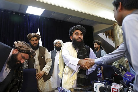 Taliban spokesman Zabihullah Mujahid, shakes hand with a journalist after his first news conference, in Kabul. (Photo | AP)