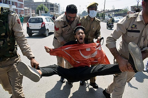 Police personnel detain a devotee during a Muharram procession, in Srinagar on Monday. (Photo | ANI)