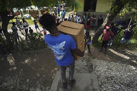 A man carries boxes of food aid from the city government to cook on site for residents displaced by the 7.2 magnitude earthquake in Les Cayes, Haiti. (Photo | AP)