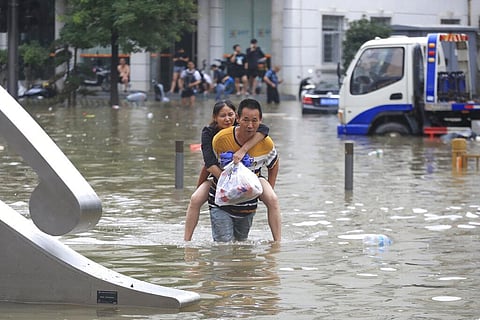 A man carries a woman along a flooded street after record downpours receded in Zhengzhou city in central China's Henan province. (Photo | AP)