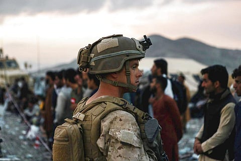A Marine assigned to Special Purpose Marine Air Ground Task Force-Crisis Response-Central Command assists evacuees during an evacuation at Hamid Karzai International Airport in Kabul. (Photo | AP)