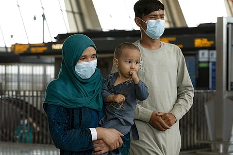 Families evacuated from Kabul, Afghanistan, walk through the terminal before boarding a bus after they arrived at Washington Dulles International Airport. (Photo | AP)
