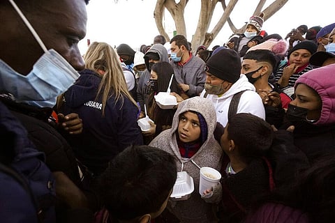 Asylum seekers receive food as they wait for news of policy changes at the border, in Tijuana, Mexico (Photo | AP)