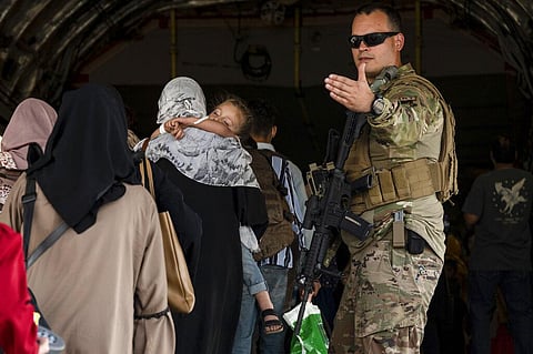 A U.S. Air Force Airman guides evacuees aboard a U.S. Air Force C-17 Globemaster III at Hamid Karzai International Airport in Kabul. (Photo | AP)