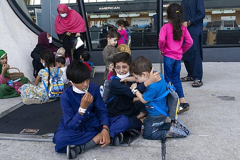 Children accompanied by their families evacuated from Kabul, Afghanistan, wait outside the terminal to board a bus after they arrived at Washington Dulles International Airport. (Photo | AP)