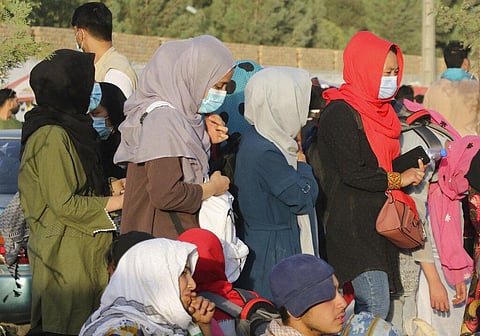 Hundreds of people gather near an evacuation control checkpoint during ongoing evacuations at Hamid Karzai International Airport. (Photo | AP)