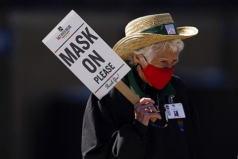 An usher holds a sign to remind fans to wear masks during a spring training baseball game in Arizona. (File Photo | AP)