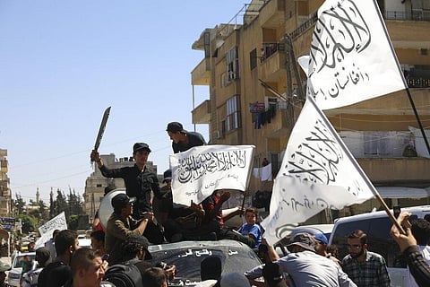 Members of the Hay'at Tahrir al-Sham, a Sunni Islamist militant group, wave the Taliban flags as they celebrate the Taliban takeover of Afghanistan, in the city of Idlib. (Photo | AP)