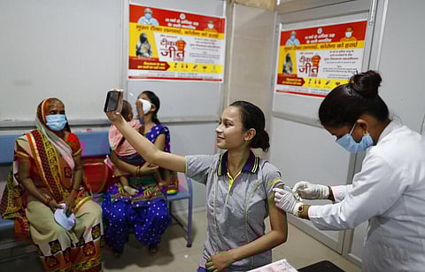 A woman takes a selfie as a health worker administers the vaccine for COVID-19 at District Govt Women's Hospital in Varanasi. (Photo | AP)