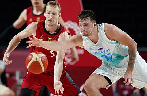 Germany's Niels Giffey (5), left, and Slovenia's Luka Doncic (77) fight for a loose ball during men's basketball quarterfinal game at the 2020 Summer Olympics. (Photo | AP)