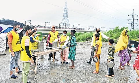 Children getting free food distributed by Civil Defence Volunteers near Shastri Park metro station on Monday. (Photo | EPS/Parveen Negi