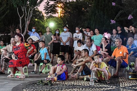 This photo taken on July 11, 2021 shows people watching the movie 'Impasse' during an outdoor screening at a park in Wuhan, in China's central Hubei province. (Photo | AFP)