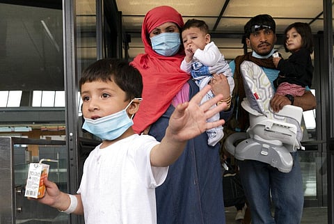 Families evacuated from Kabul, Afghanistan, walk through the terminal before boarding a bus after they arrived at Washington Dulles International Airport. (Photo | AP)