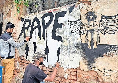 Mysuru artists Rahul and Sumanth Gowda paint a wall with a message demanding stricter punishment to those who commit heinous crimes like rape, in Mysuru on Sunday. (Photo | Udayshankar S, EPS)