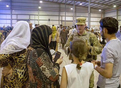 An airman provides assistance to evacuees from Afghanistan, at Al Udeid Air Base, Qatar. (Photo | AP)