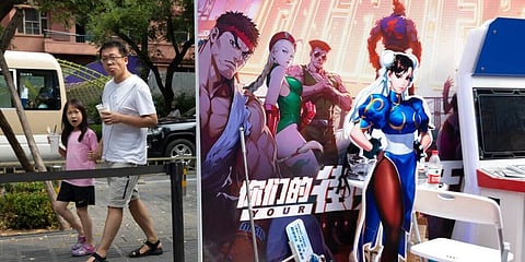 A man and a child past by a promotion for computer games in Beijing. (File Photo | AP)