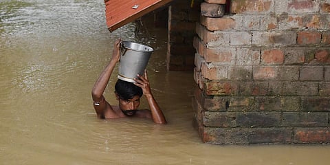 A man comes out with his belongings after his house submerged in flood water at Udaynarayanpur in Howrah district. (Photo| PTI)