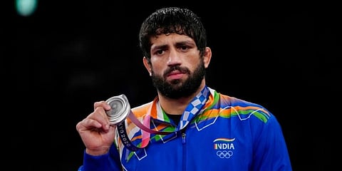 Silver medalist India's Ravi Kumar celebrates on the podium for the men's 57kg Freestyle wrestling. (Photo | AP)
