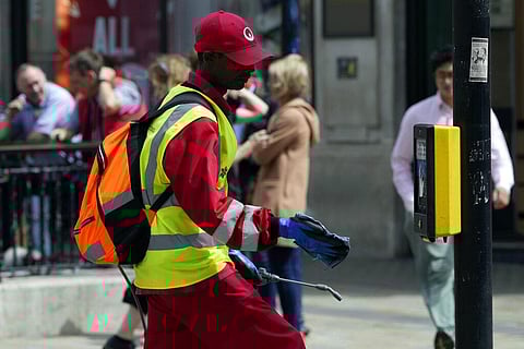 A Westminster Council contractor cleans the pedestrian crossing buttons with antibacterial agents against the coronavirus in London. (Photo | AP)