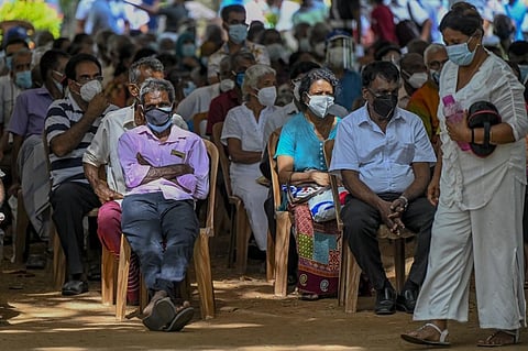 People sit in a queue as they wait to receive a dose of the AstraZeneca vaccine against the Covid-19 coronavirus in Colombo on August 5, 2021. (Photo | AFP)