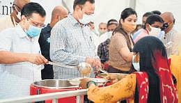 CM Arvind Kejriwal serves food to a beneficiary in Delhi on Sunday. (Photo | Twitter)