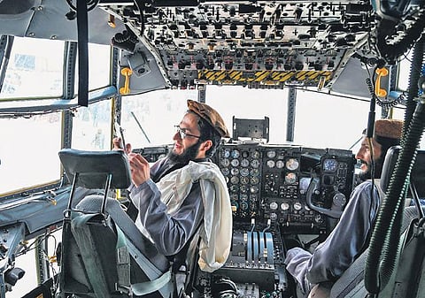 Taliban fighters in the cockpit of an Afghan Air Force plane at Kabul airport | ap/afp