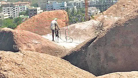 A worker clearing the rock formations in Fakhruddin Gutta, Gachibowli. (Photo | Express)