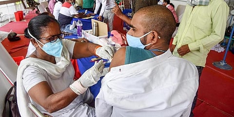 A health worker administers a dose of COVID-19 vaccine to beneficiaries as others wait for their turn, in Patna on Friday. (Photo | PTI)