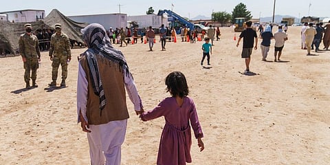 A man walks with a child through Fort Bliss' Doña Ana Village where Afghan refugees are being housed, in New Mexico, Friday, Sept. 10, 2021. (Photo | AP)