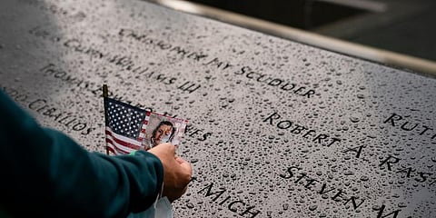 A visitor touches an American flag with an image of of Jill Maurer-Campbell, who died on Sept. 11, as it stands beside her name at the National September 11 Memorial & Museum, New York. (Photo | AP)