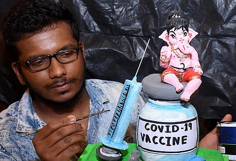An artiste gives finishing touches to a Ganesha idol promoting Covid-19 vaccination in Mysuru. (Photo | Udayshankar S, EPS)