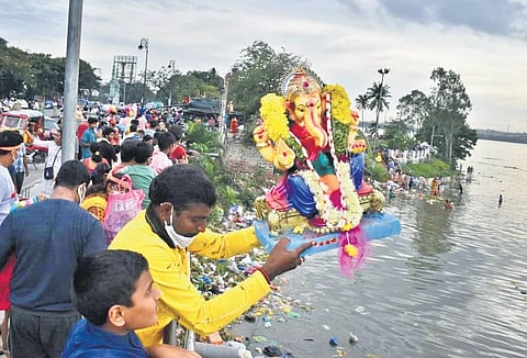 A devotee drops a Ganesha idol in Hussainsagar, in Hyderabad on Sunday. (Photo | S Senbagapandiyan)