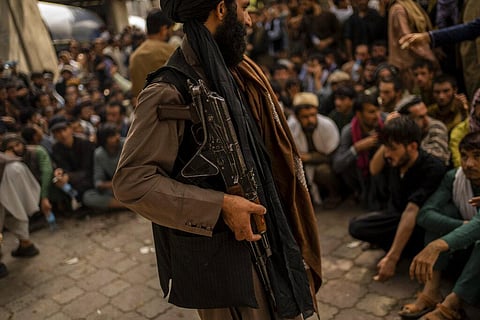 A Taliban fighter controls a crowd waiting to withdraw money from a bank branch in Kabul, Afghanistan, Sunday, Sept. 12, 2021. (Photo | AP)