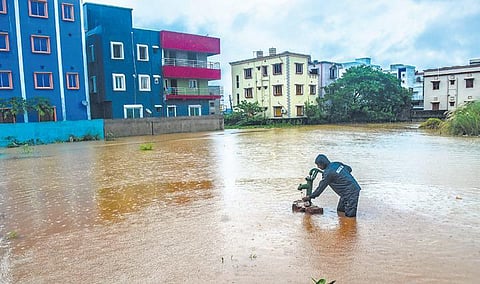 A man collects water from a submerged tubewell at Mahadev Nagar near Jharpada; the waterlogged WATCO plant at Basuaghai near Tankapani road in Bhubaneswar. (Photo | Biswanath Swain, EPS)
